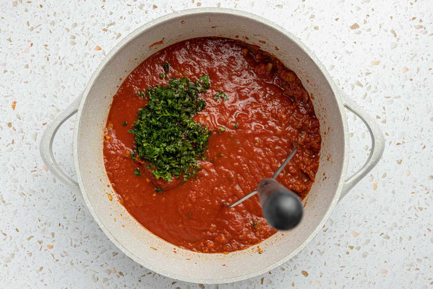 Herbs Added to Pot While Canned Tomatoes Is Smashed Using a Potato Smasher for Spaghetti & Meatballs Recipe