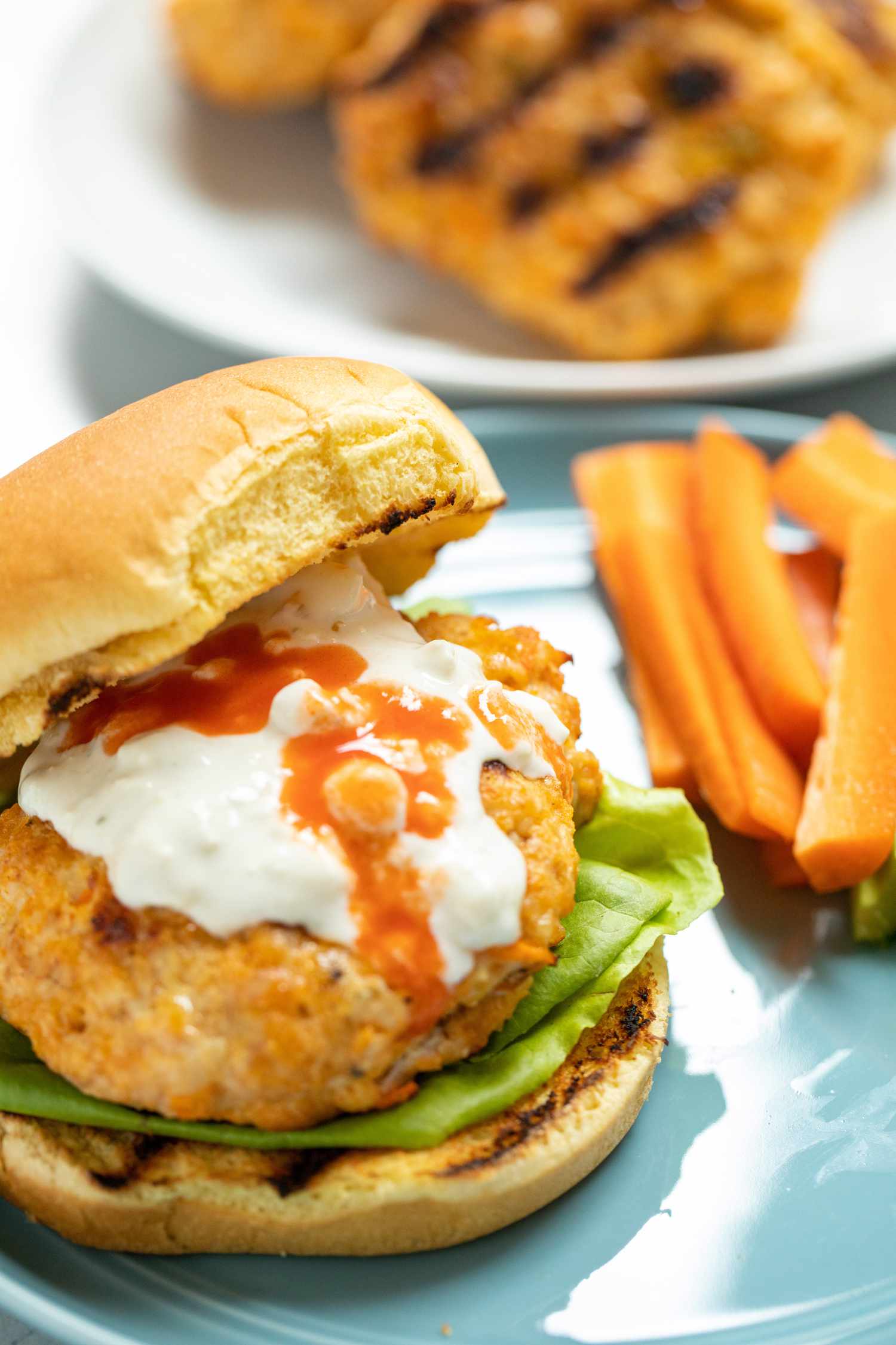 The top bun set to the side of the BEST spicy buffalo chicken burger.