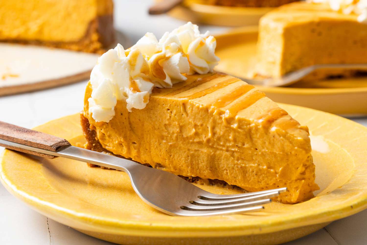 No-bake cheesecake on a small plate with a fork, and in the surroundings, more small plates with a slice and the platter with the rest of the cheesecake