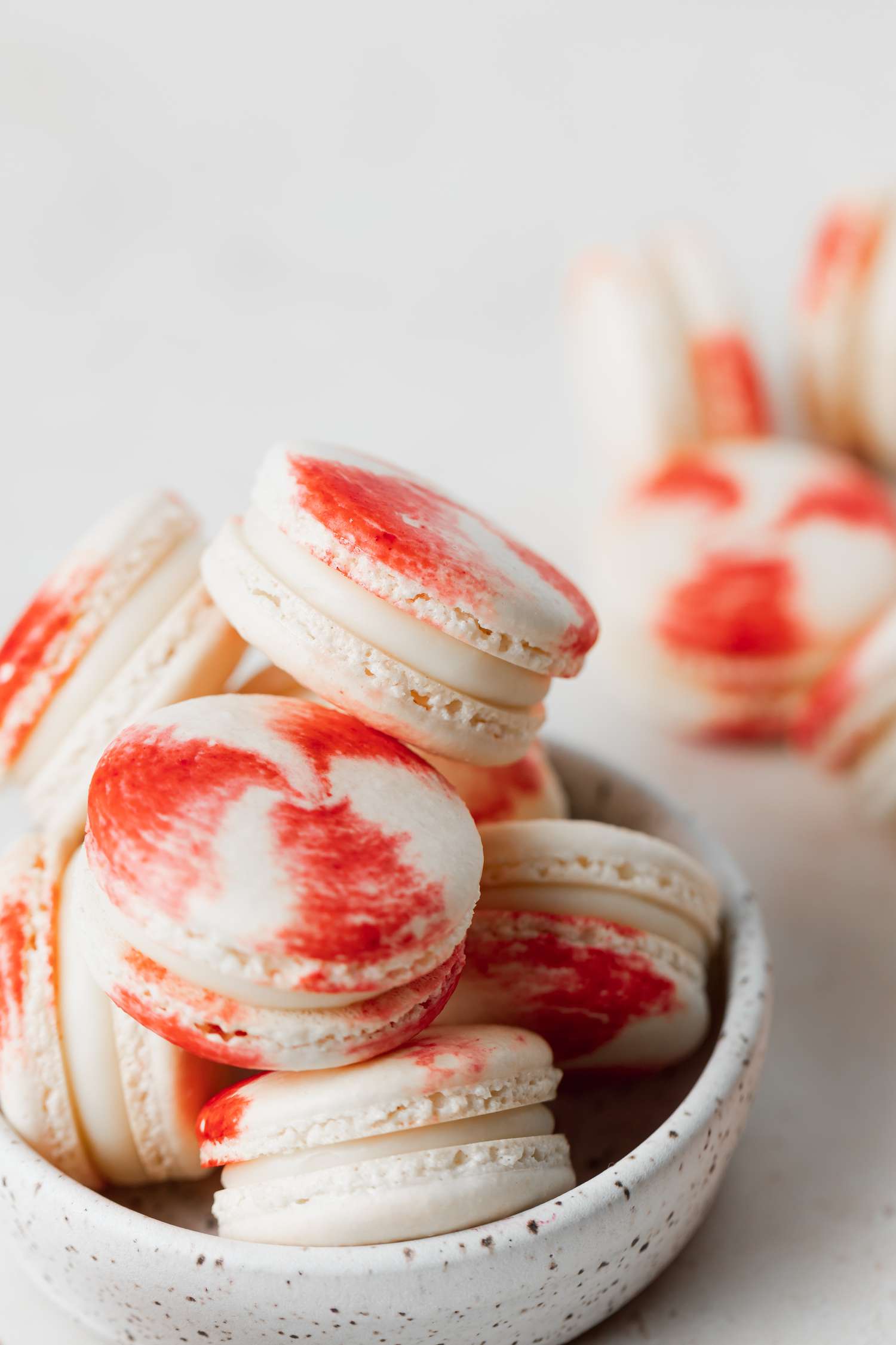 Peppermint macarons with white chocolate filling stacked in a bowl.