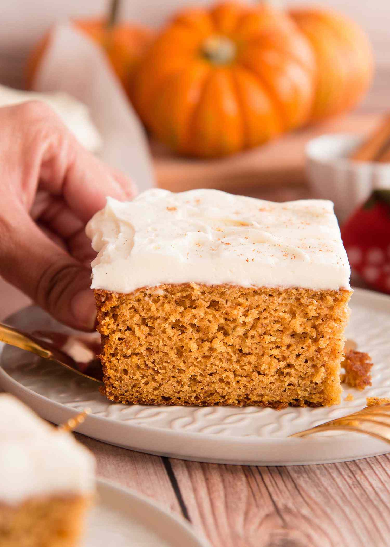 Side view of The Best Pumpkin Cake with Cream Cheese Frosting being placed on a plate.