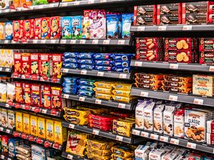 Grocery store shelves stocked with various packaged snacks including cookies crackers and chips