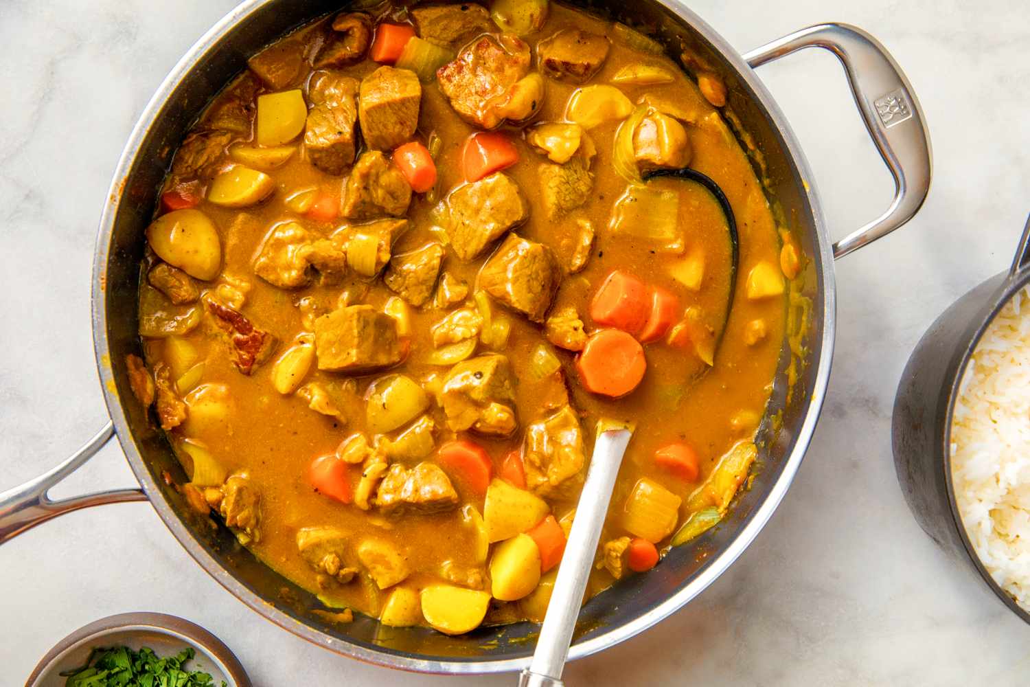 A pot of Japanese curry with vegetables and meat a spoon visible in the pot