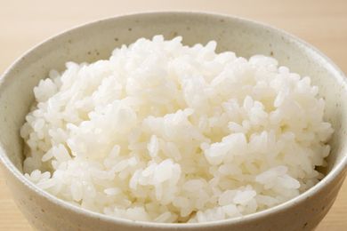 A bowl filled with cooked white rice placed on a lightcolored surface