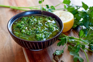 Zhoug in a small black bowl with olive oil on top.
