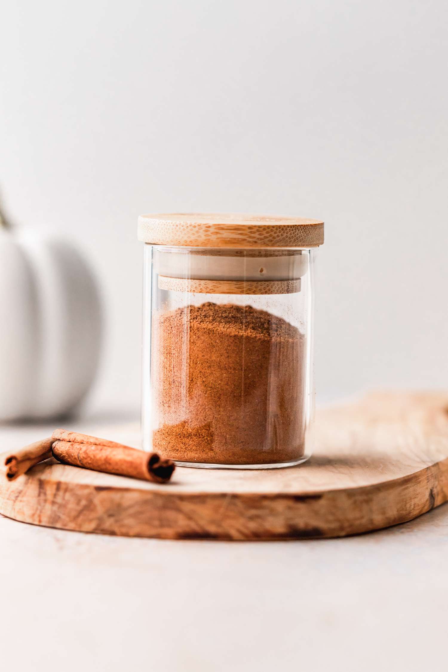 Homemade pumpkin pie spice blend in a jar on a wooden cutting board.