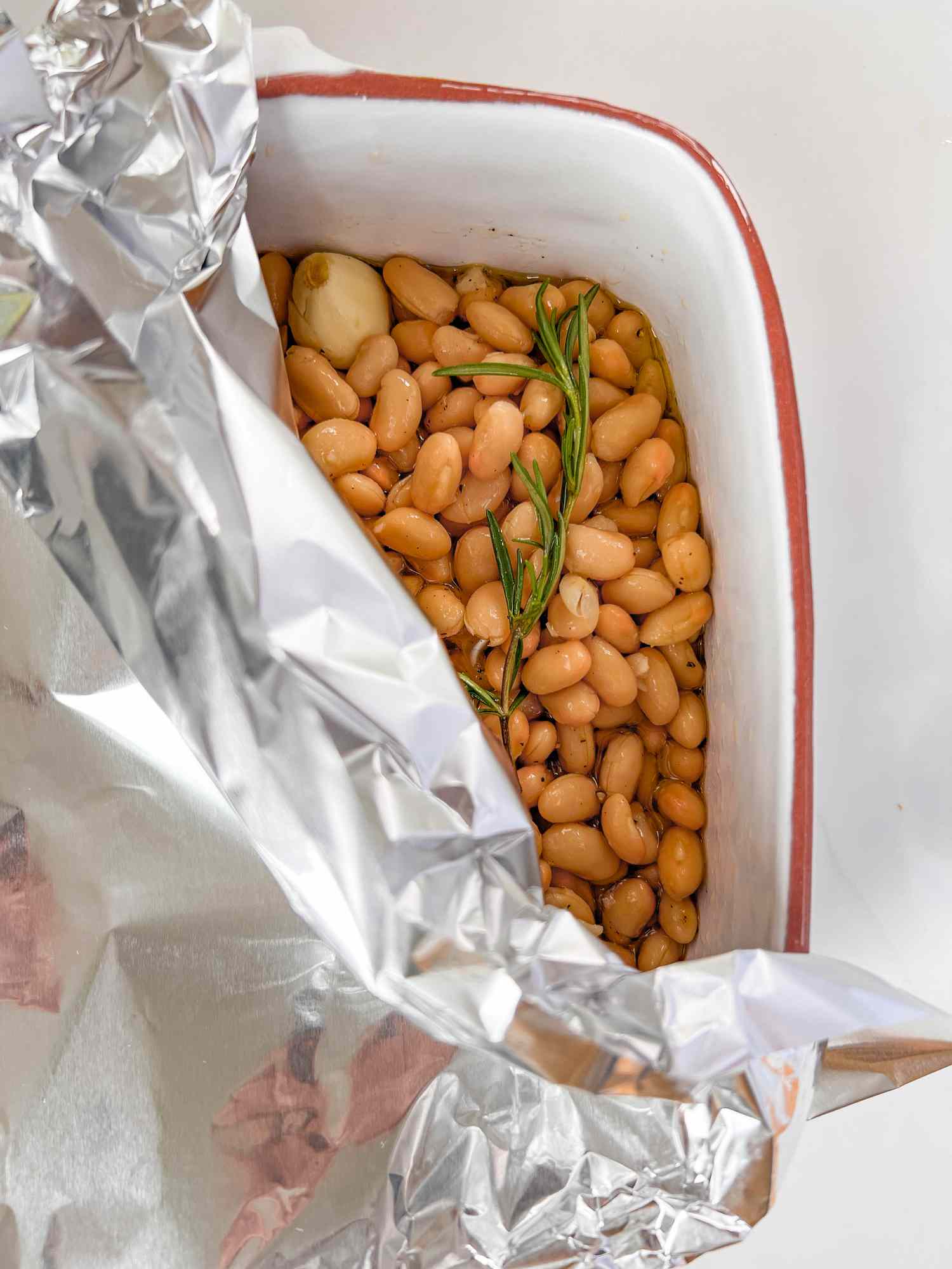 beans, rosemary, and garlic in a white casserole dish