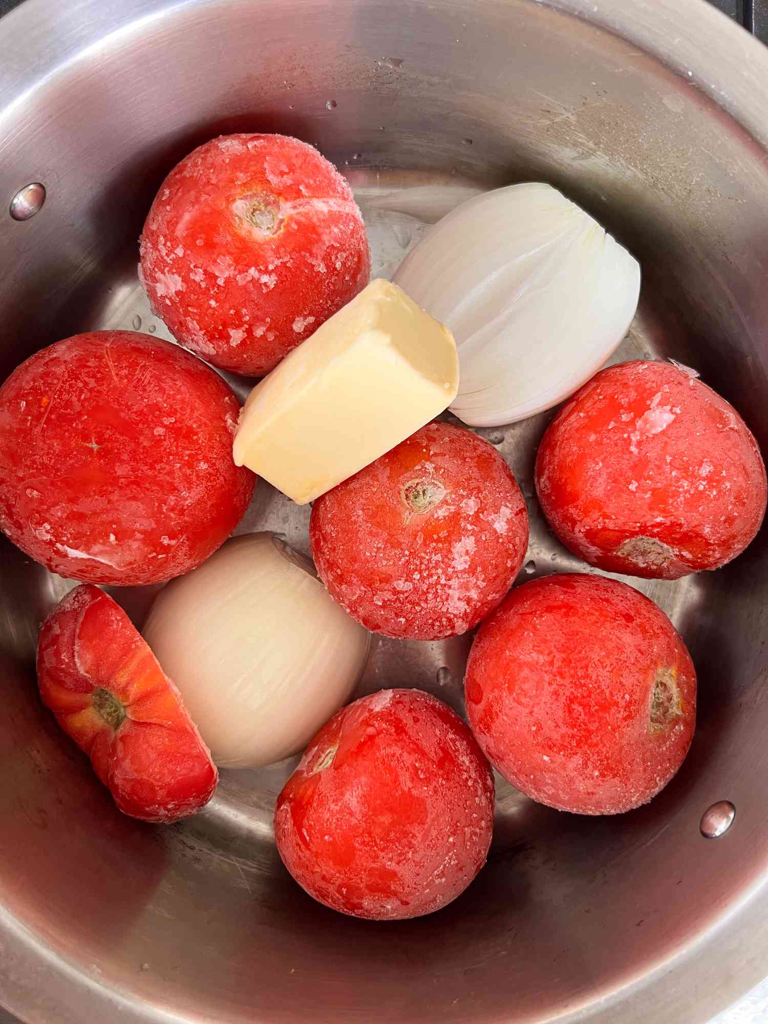 Frozen tomatoes, butter, and onion in a pot