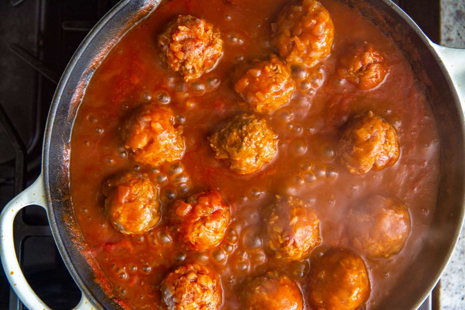Meatballs cooking in a pot of sauce