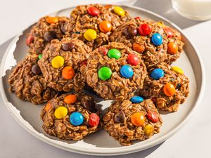 Plate of no-bake m&m cookies next to a glass of milk