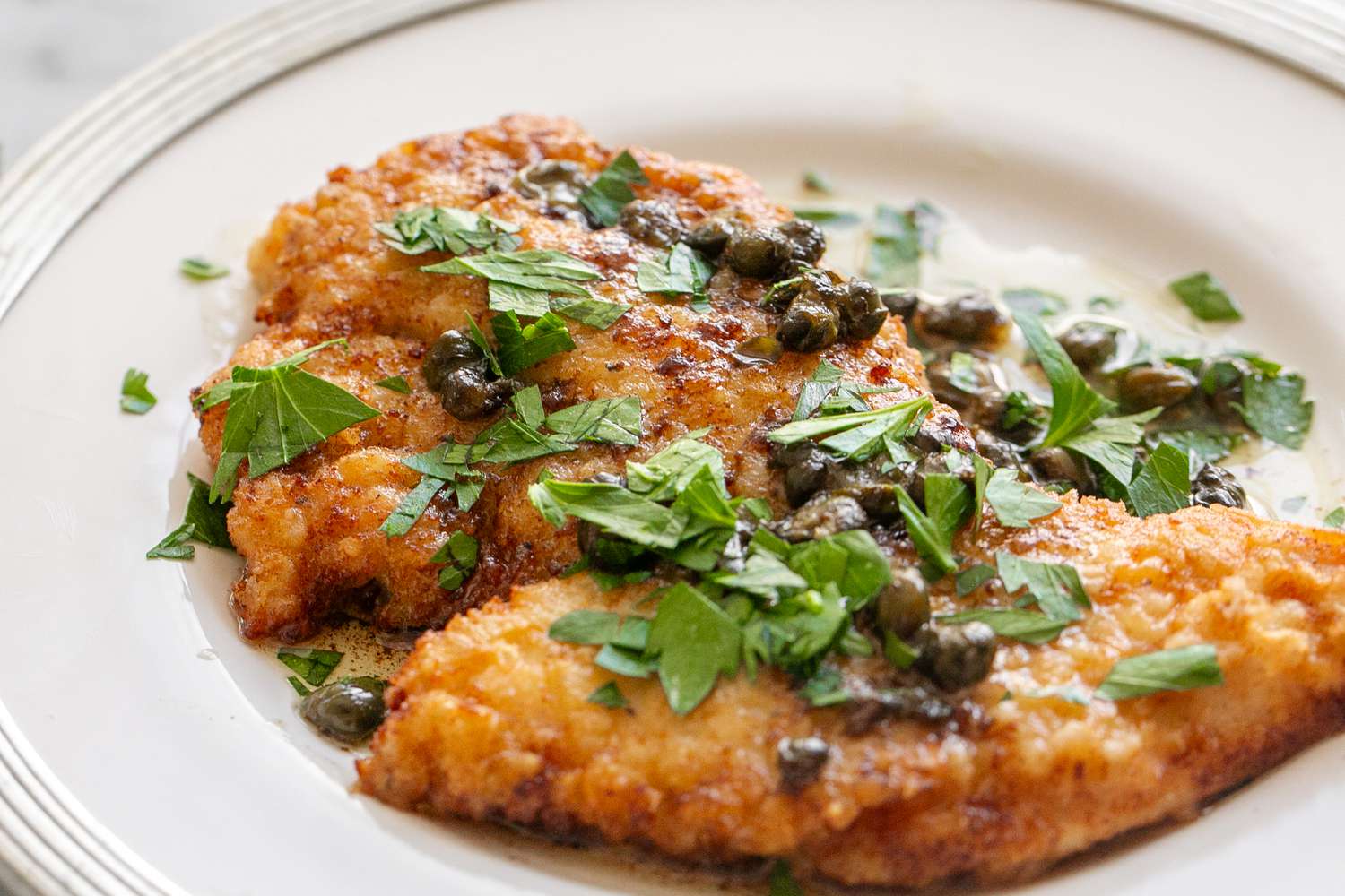 A helping of chicken piccata on a plate topped with sauce