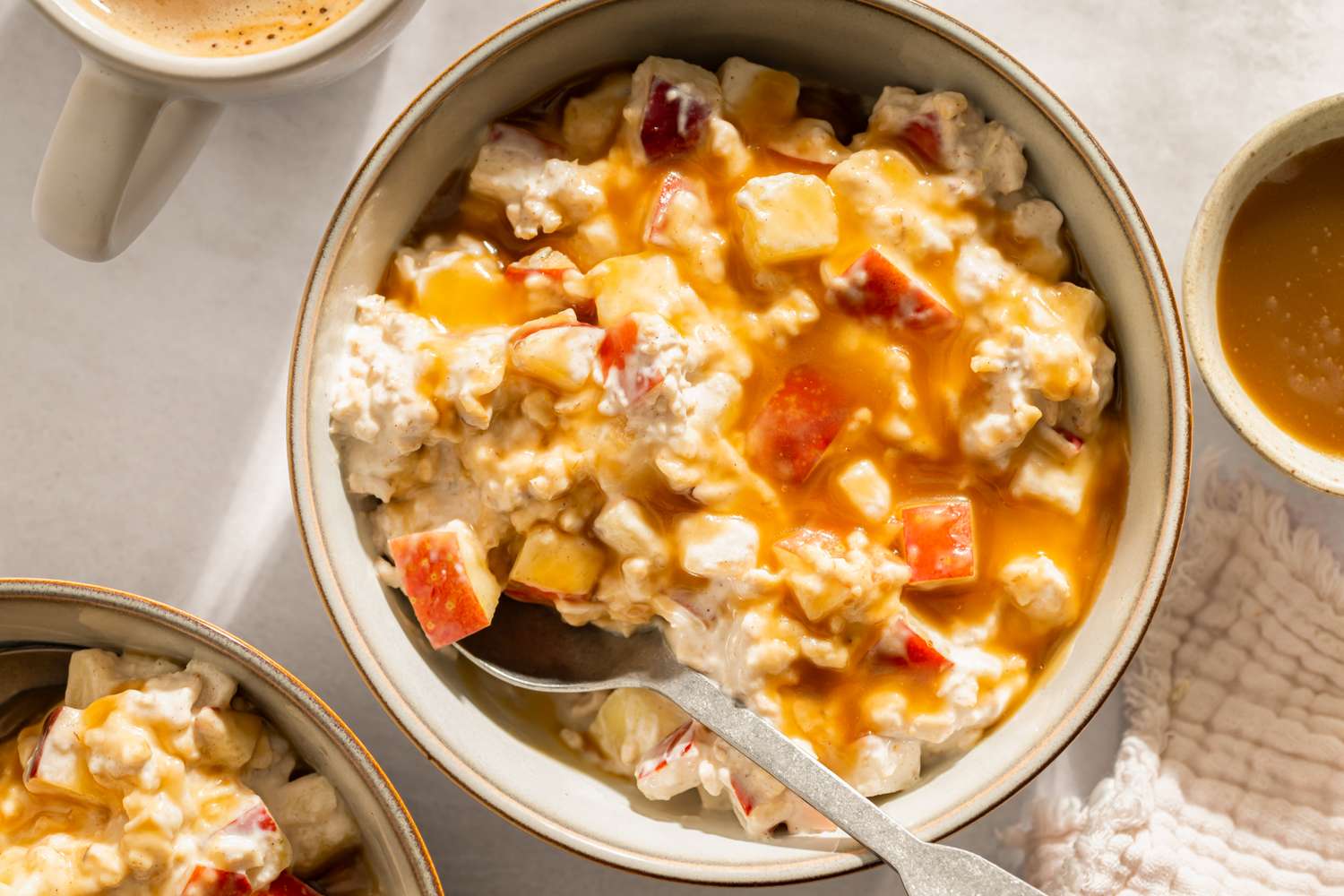 A bowl of overnight oats topped with diced apple and caramel drizzle