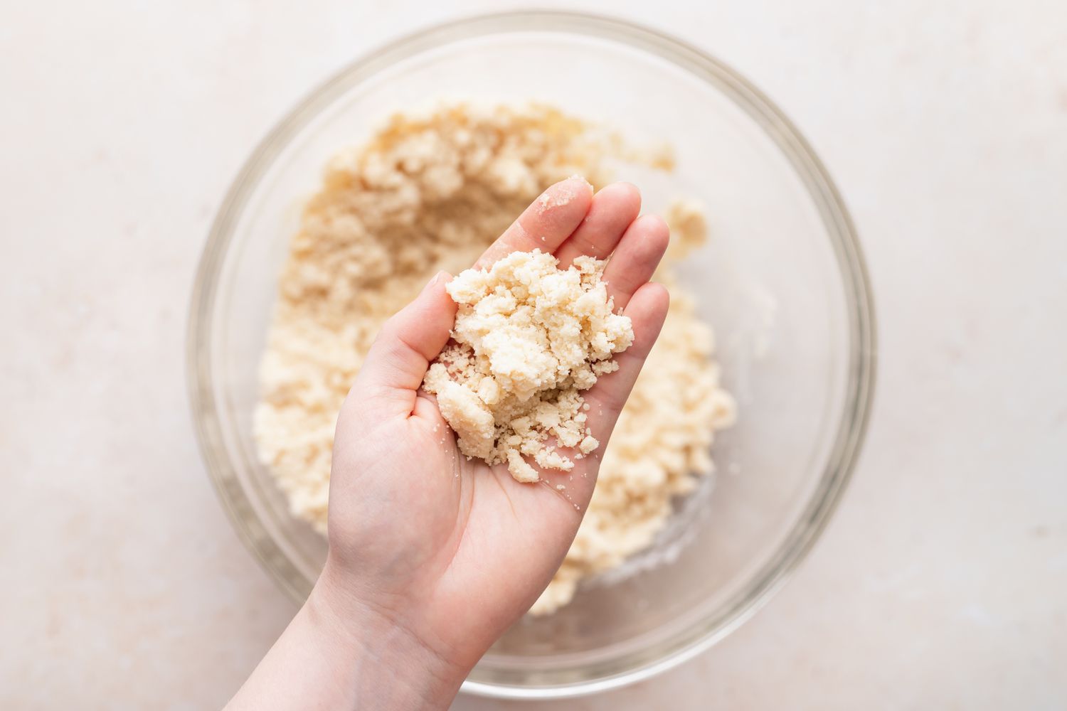 Dough for almond crescent cookies pressed on a person's hand.
