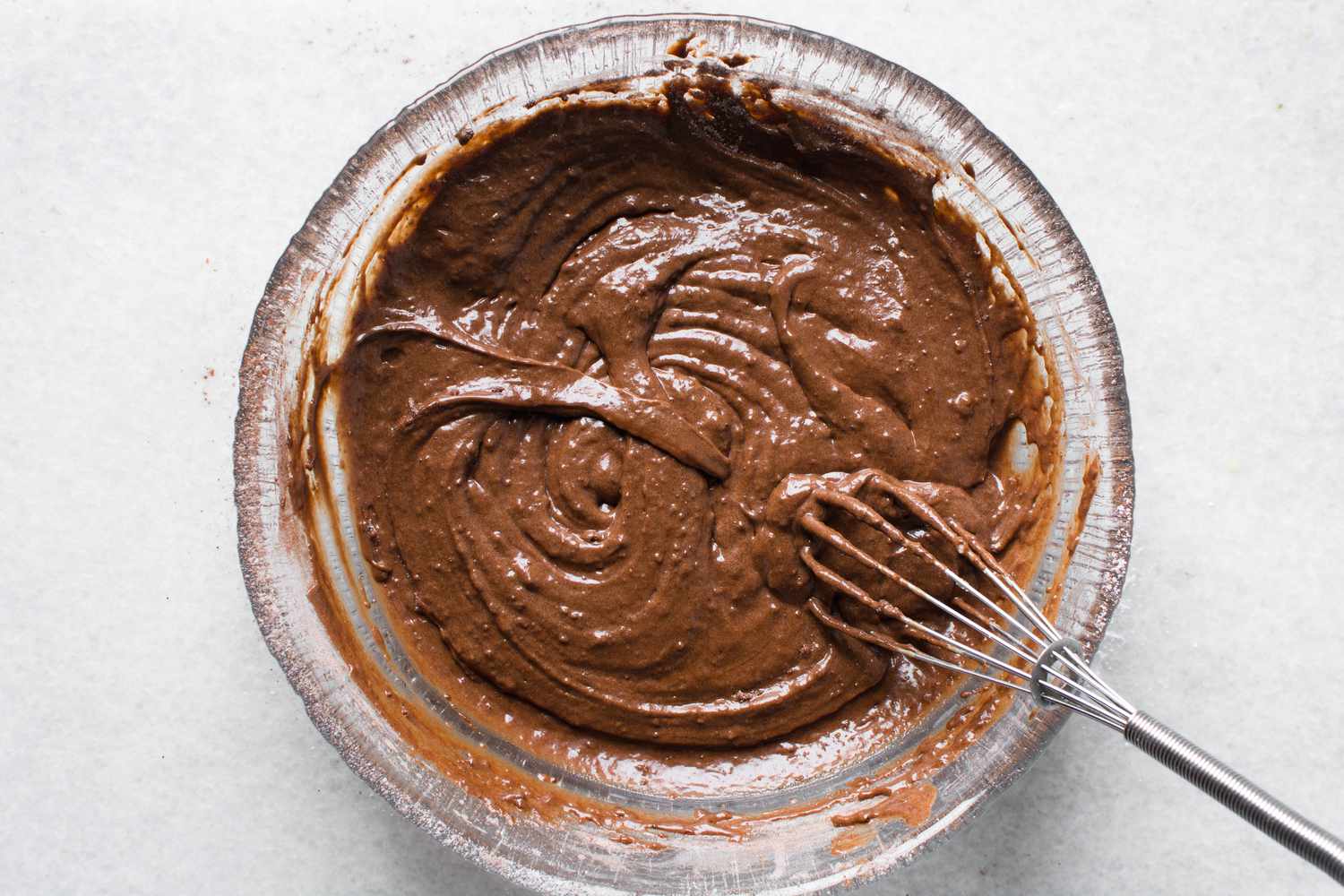 Chocolate batter in a glass bowl with a whisk