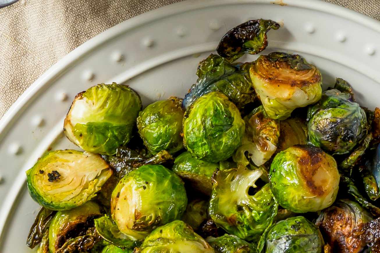Overhead view of a white plate of roasted Brussels sprout halves