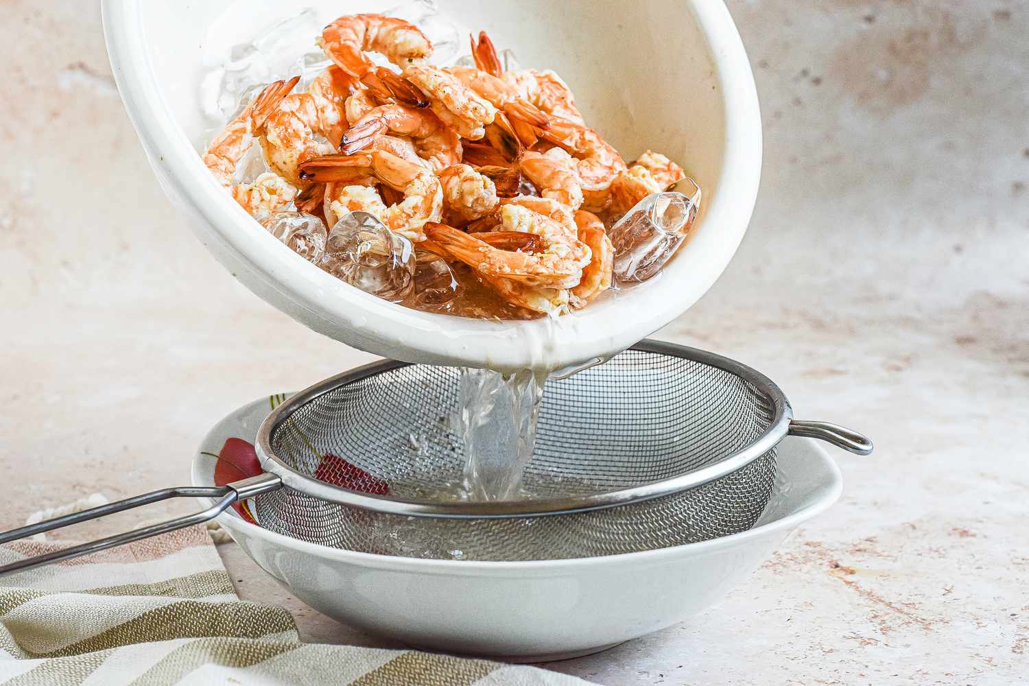 Cooling boiled shrimp in an ice bath for a shrimp cocktail recipe