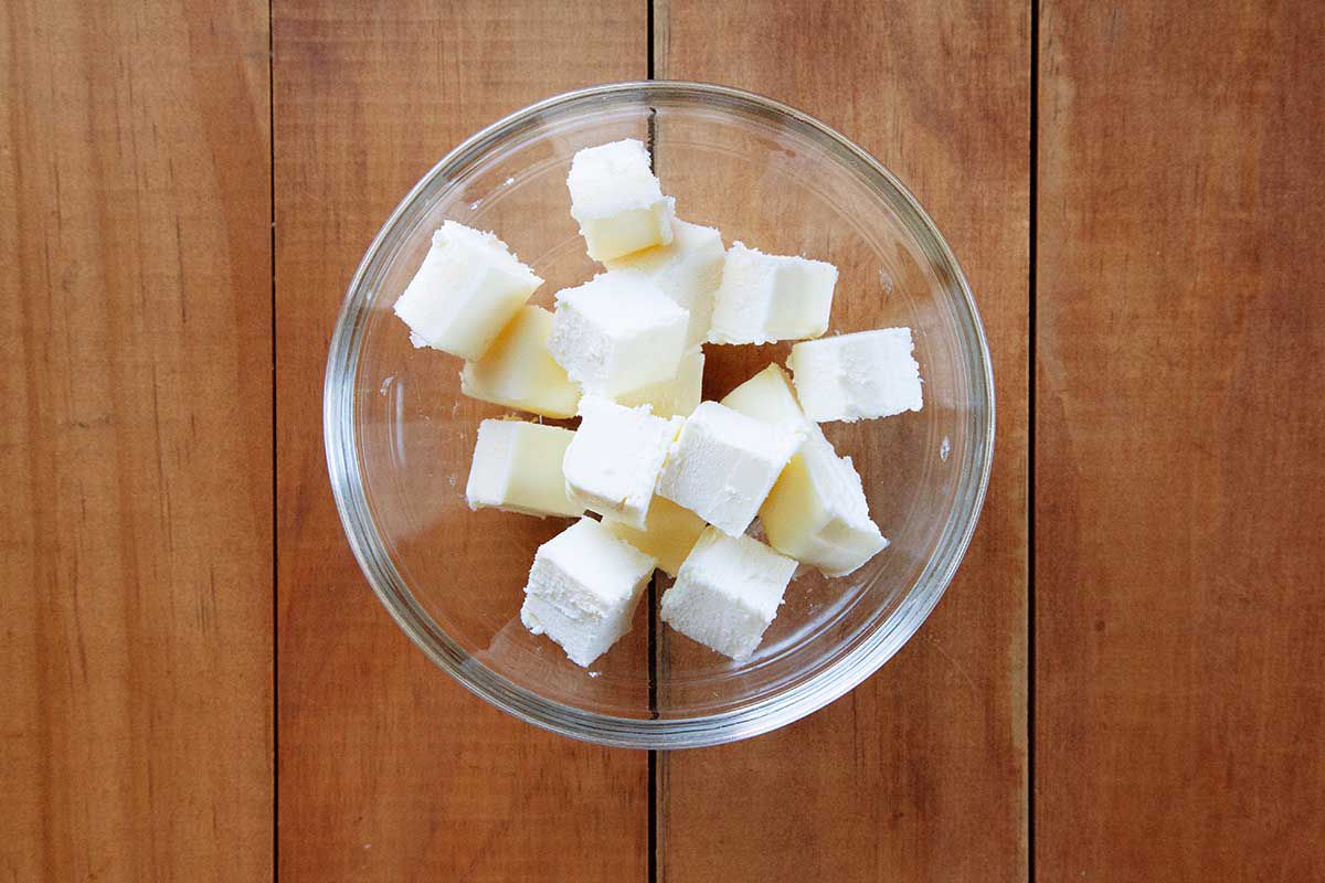 Cubed butter in a small glass dish and sitting on a wooden table.