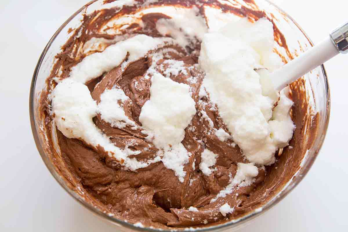 gently folding beaten egg whites into chocolate cake batter