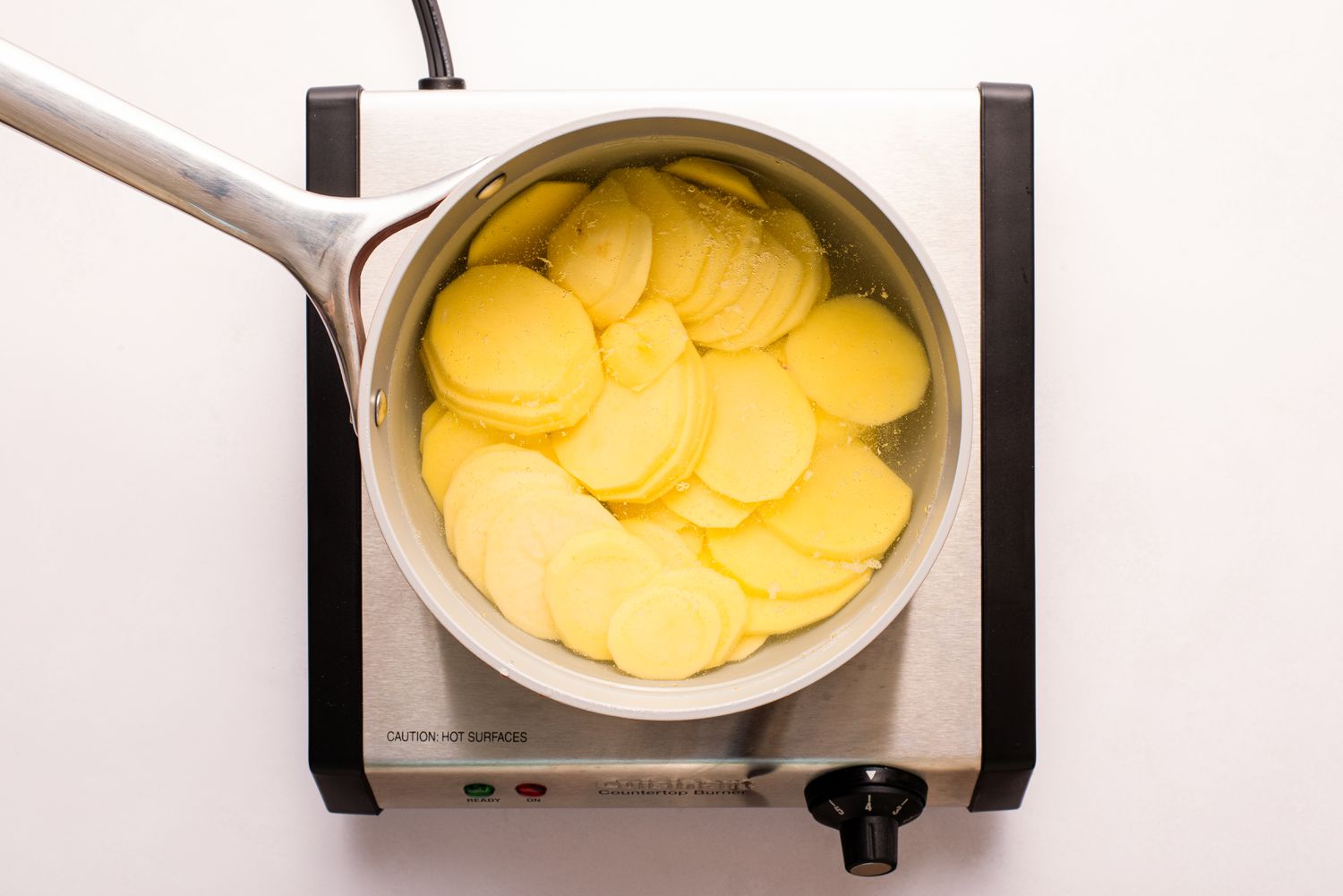 sliced yukon gold potatoes boiling in a pot of salted water for Lyonnaise potatoes recipe