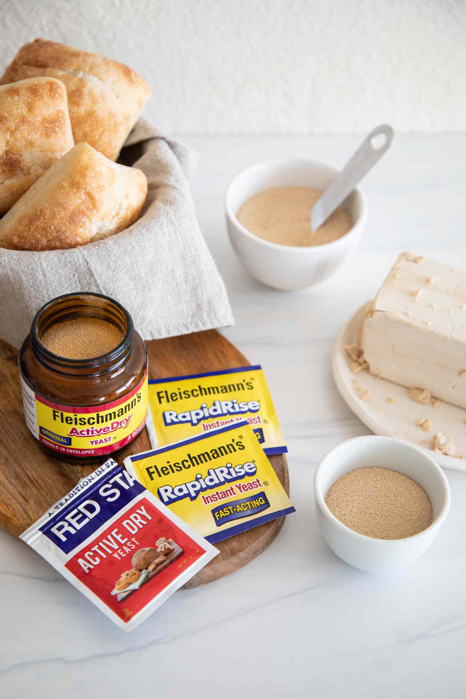 Side view of different types of yeast and a bowl with bread behind them.