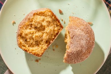 An apple cider donut muffin, broken in half and on a plate