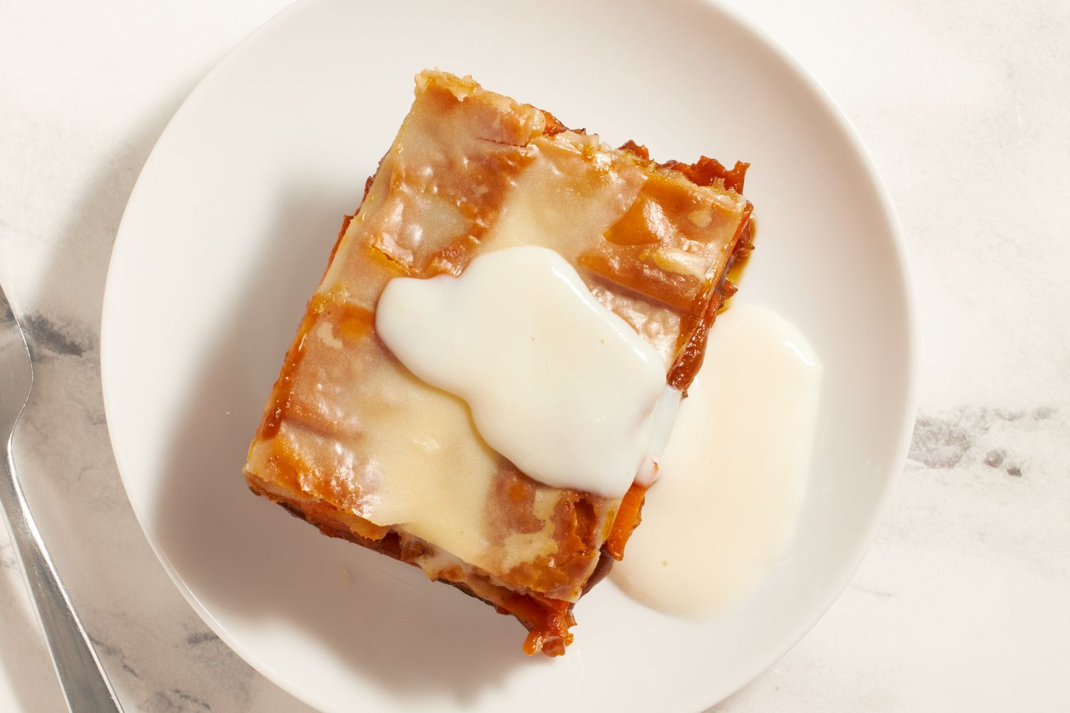 A piece of sweet potato sonker with a glaze served on a white plate