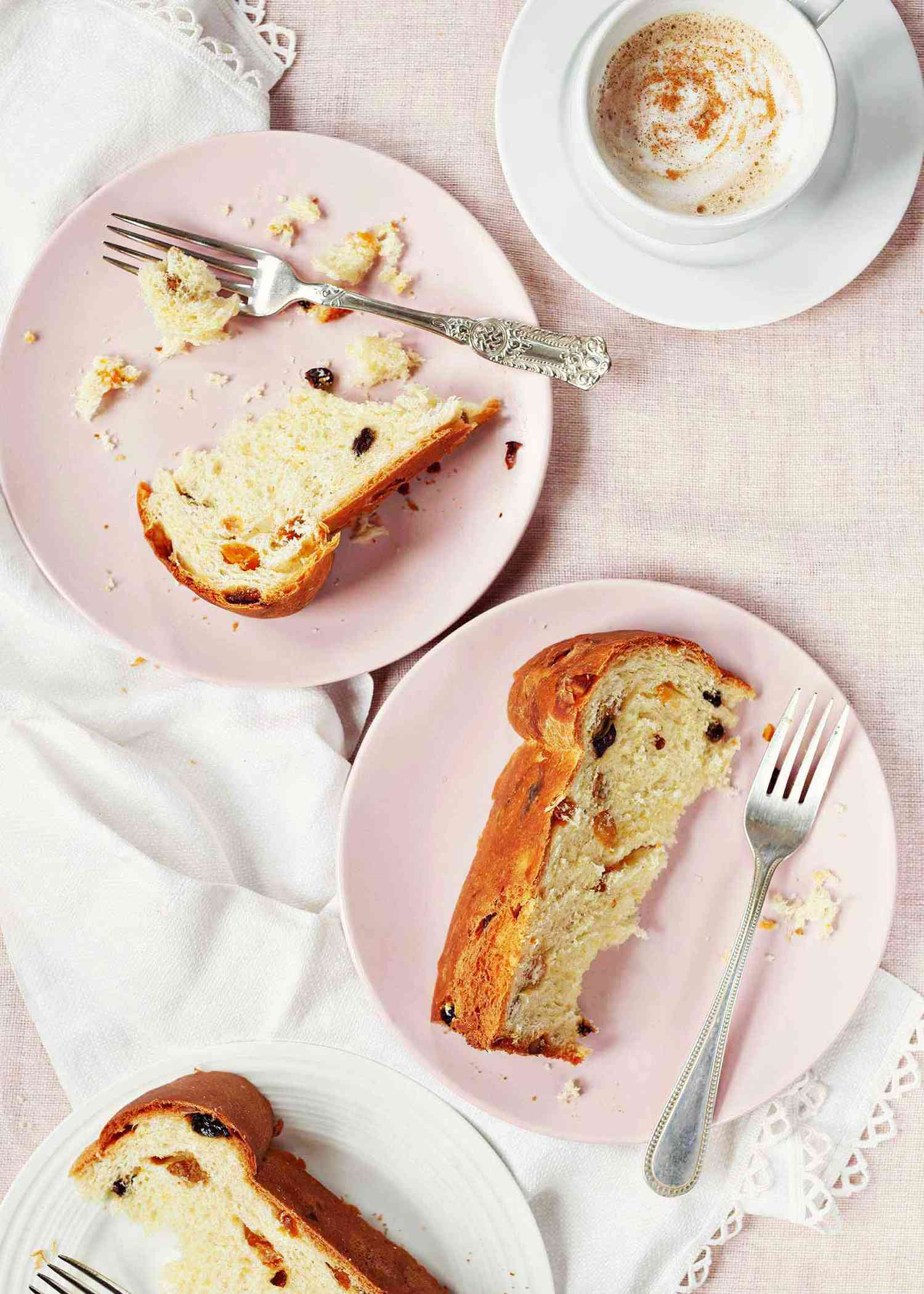 Three slices of easy homemade panettone on pink plates with forks.