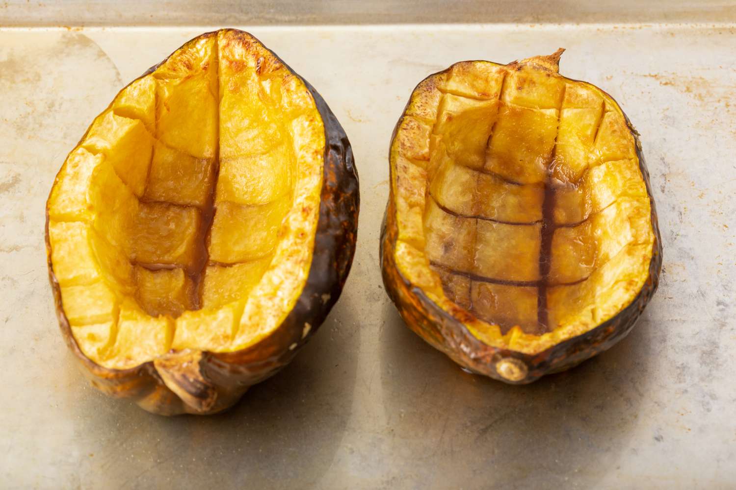 Two halves of roasted acorn squash on a counter.