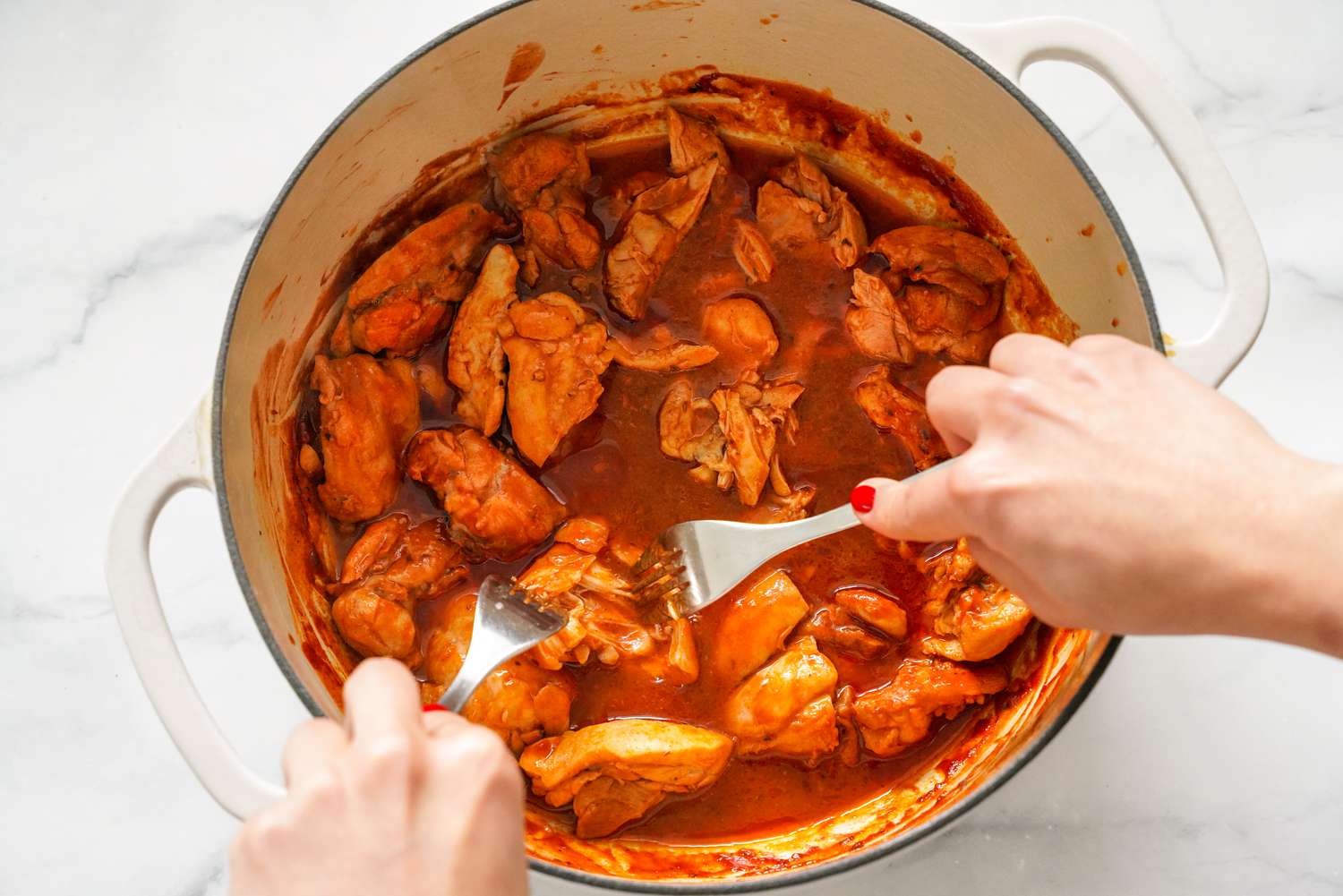 Fork Used to Shred Chicken Pieces in the Dutch Oven