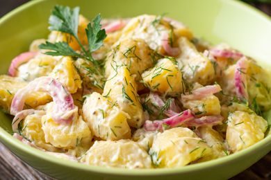 potato salad in a bowl topped with dill and parsley