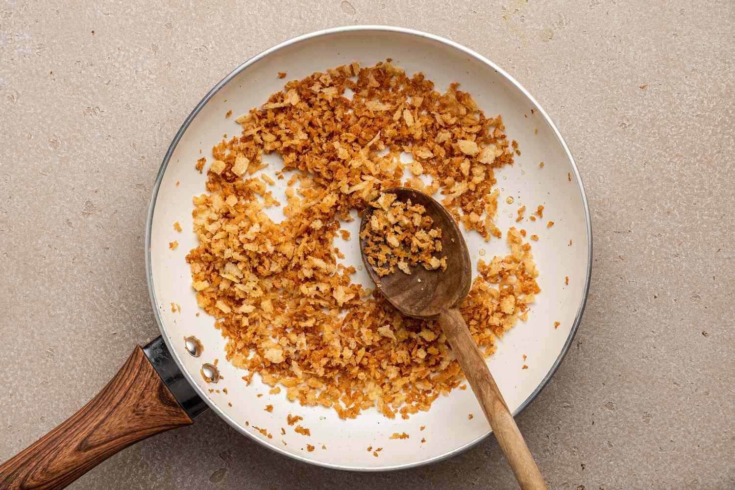 Skillet of Toasted Breadcrumbs Mixed with a Wooden Spoon for Brussels Sprouts Caesar Salad with Lemony Breadcrumbs Recipe