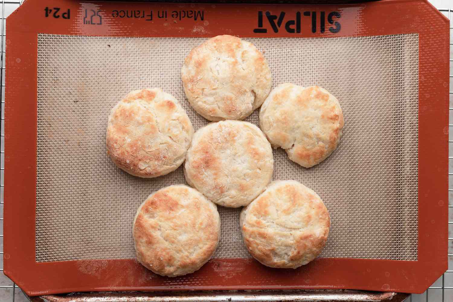 Overhead view of baked biscuits on a baking sheet to make biscuits and gravy.