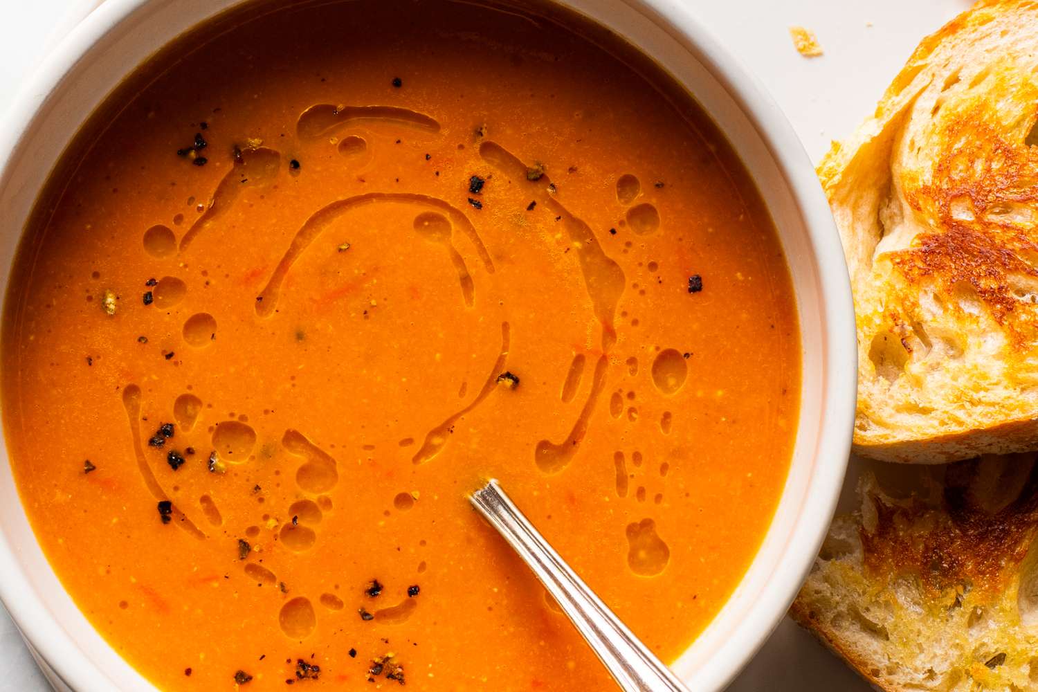 Bowl of tomato red lentil soup with bread on the side