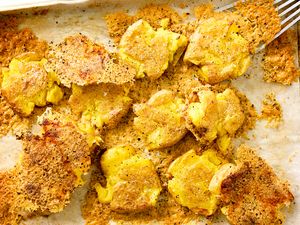 Crispy Parmesan Smashed Potatoes on a parchment lined sheet-pan
