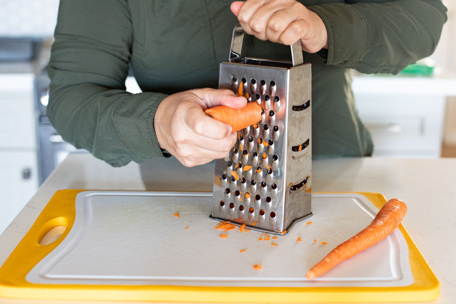 Carrots Grated over a Cutting Board for Zucchini Carrot Bread Recipe