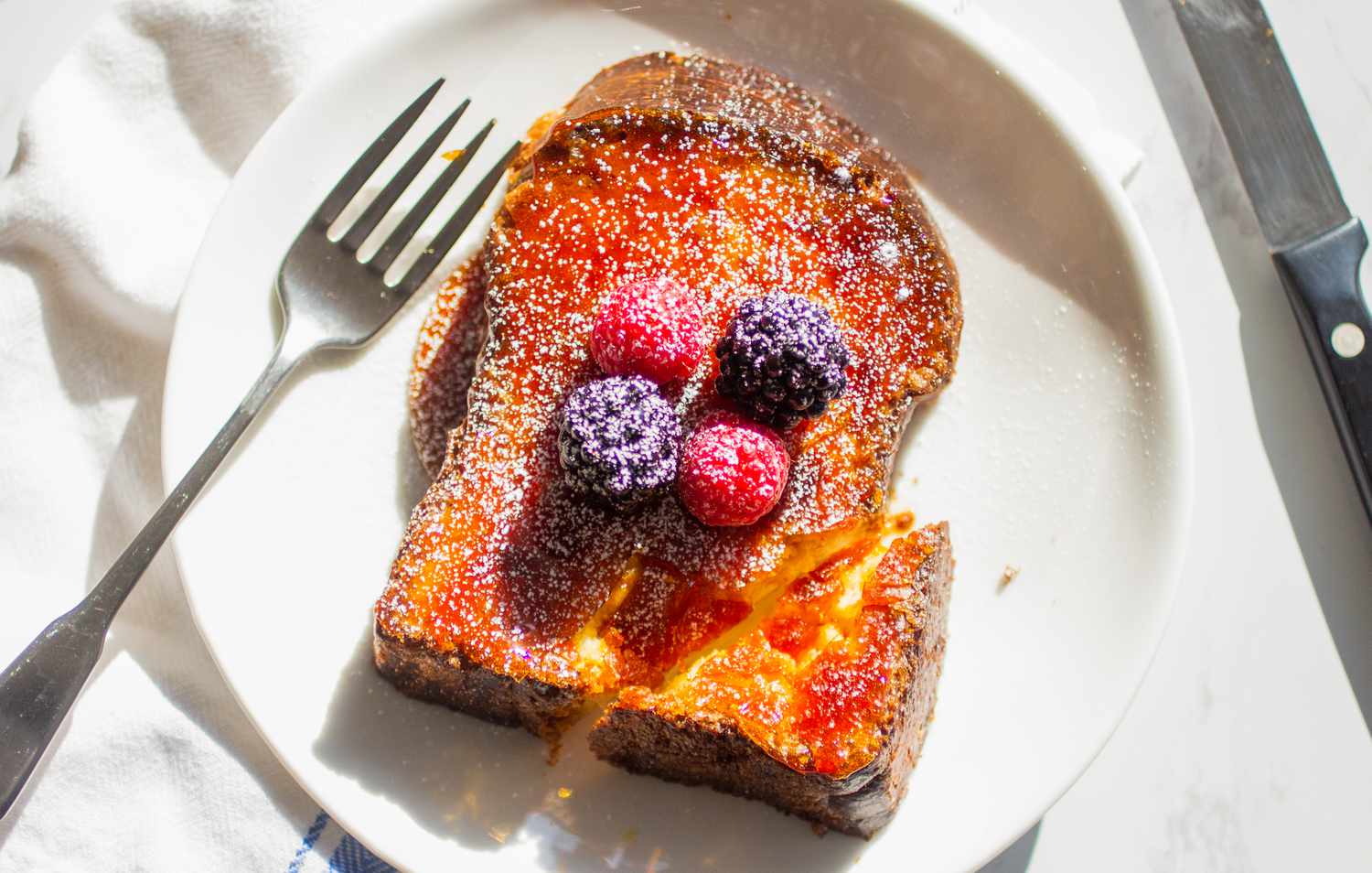 creme brulee french toast topped with berries and powdered sugar