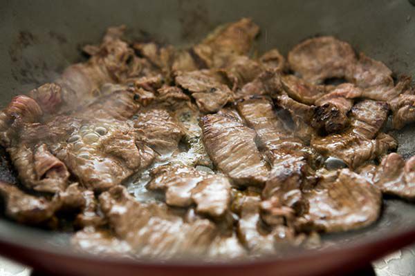 beef strips being cooked in pan
