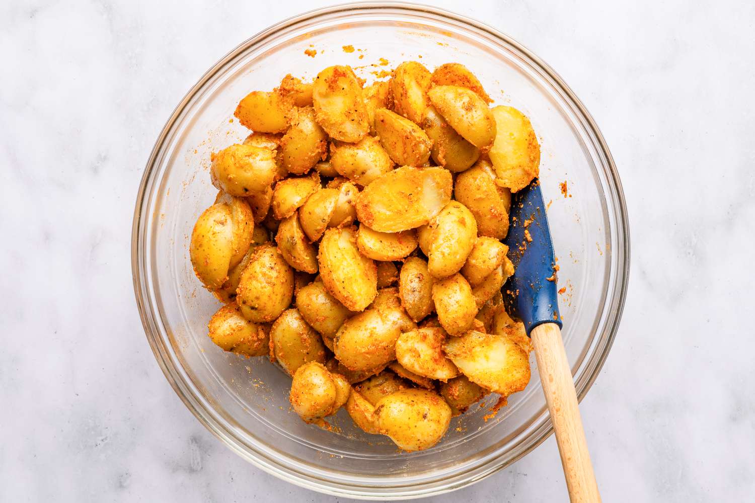 potatoes mixed with seasoning in a bowl for bang bang potatoes recipe