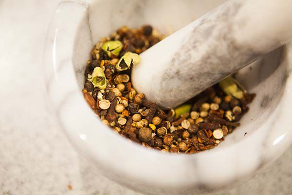 Herbs and spices being crushed by a mortar and pestle
