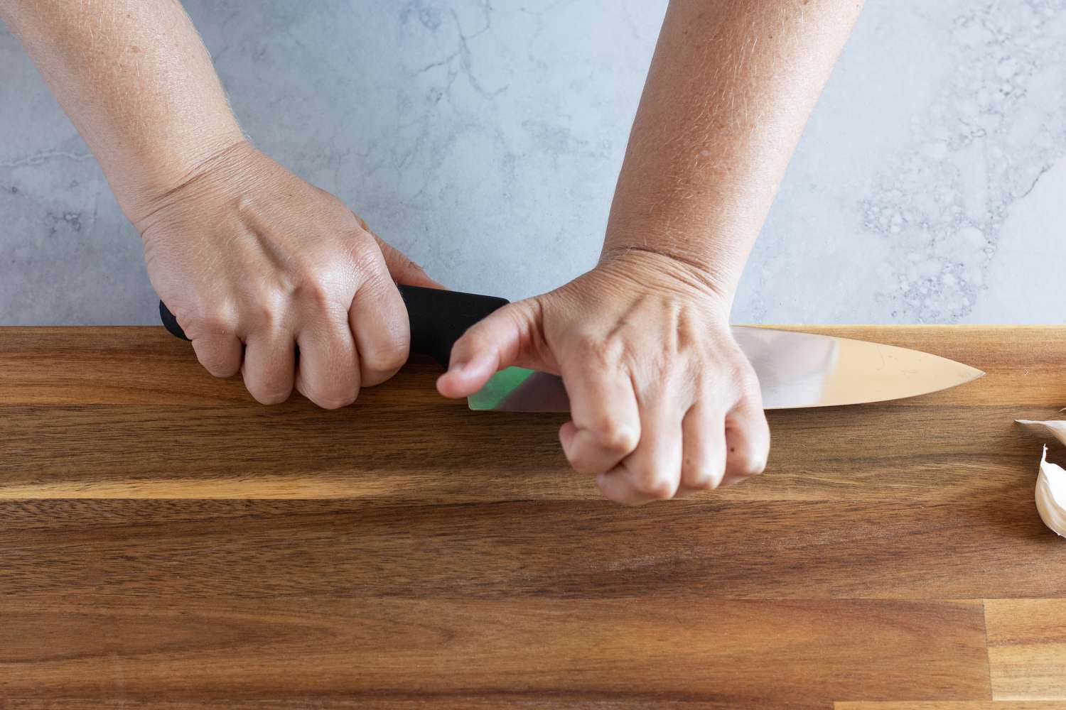Pushing down on chef's knife to peel a clove of garlic