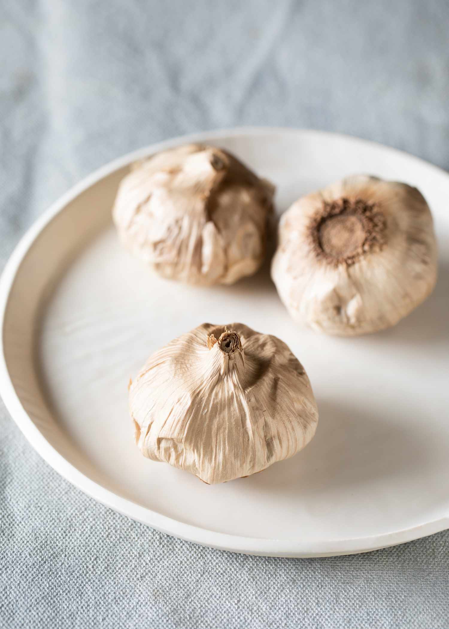 Three heads of black garlic on a plate.