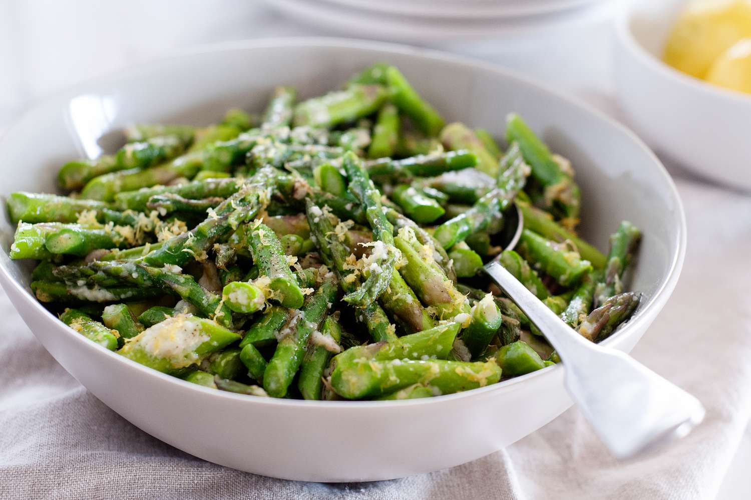 Asparagus with shredded Parmesan in a bowl with a spoon