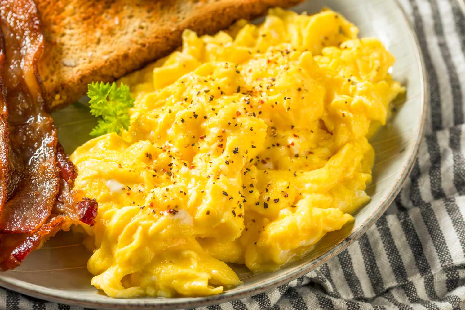 Scrambled eggs on a plate with bacon and toast