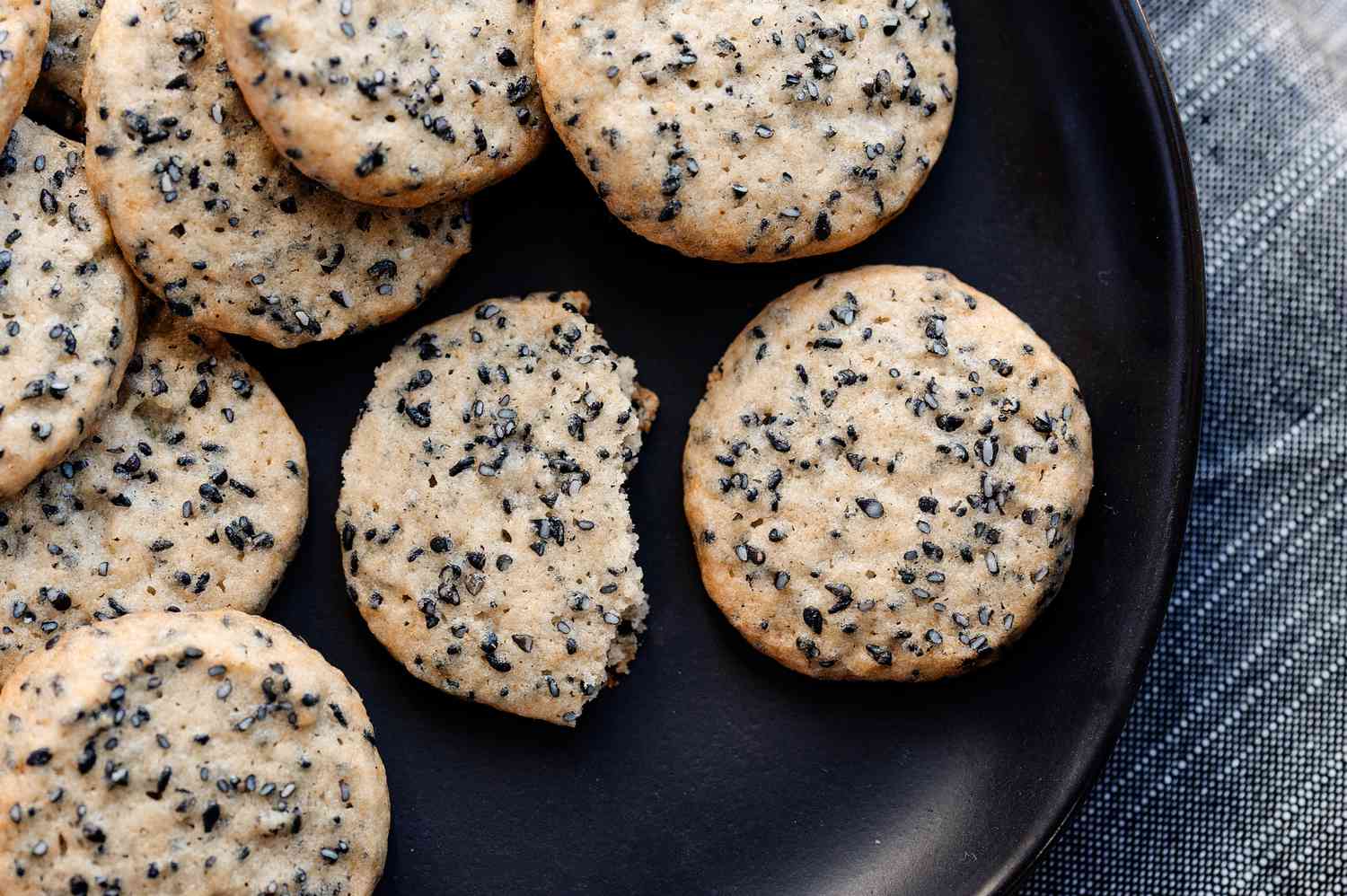Overhead view of slice and bake sesame cookies on a black background.