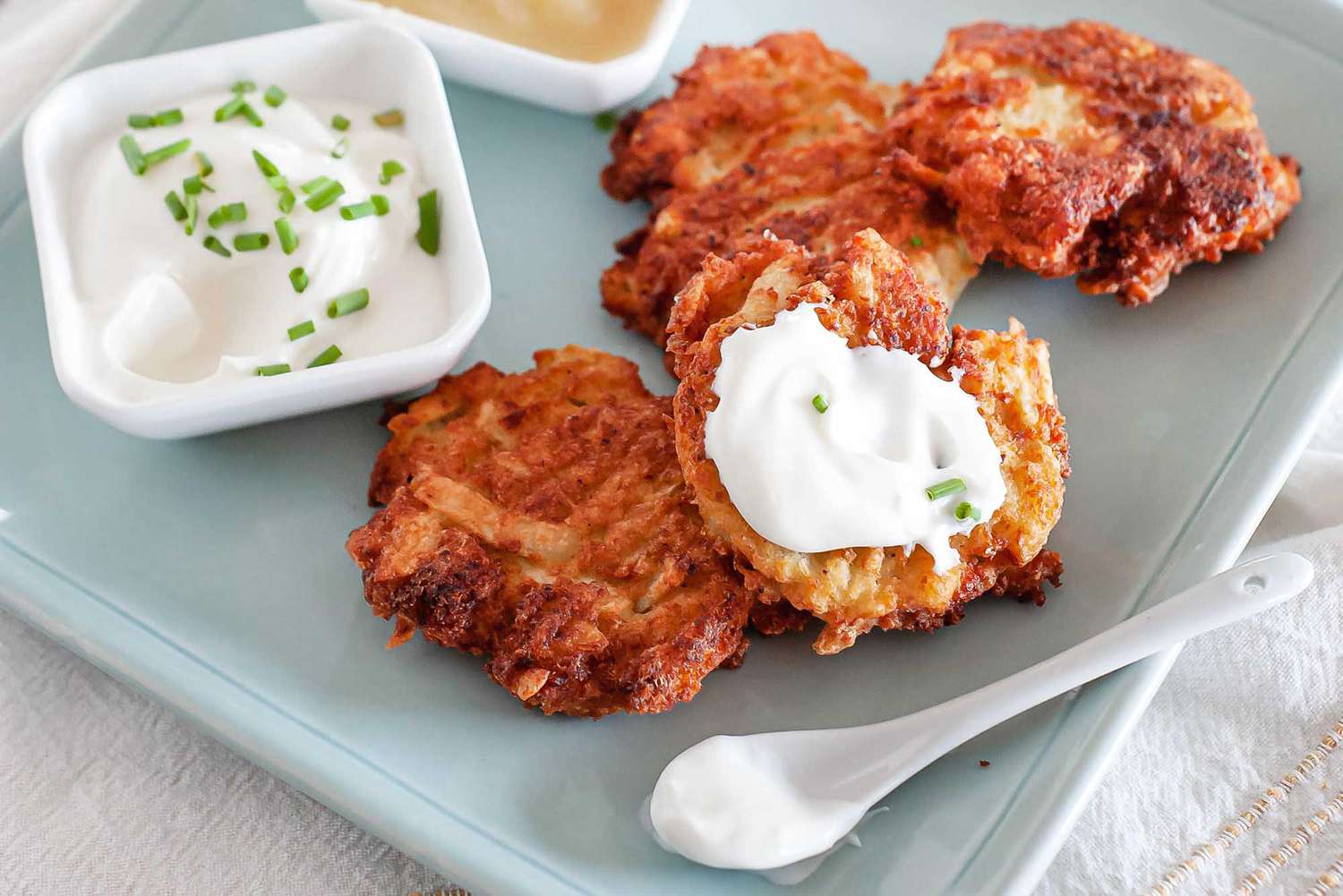 the best potato latkes on a blue platter with sour cream