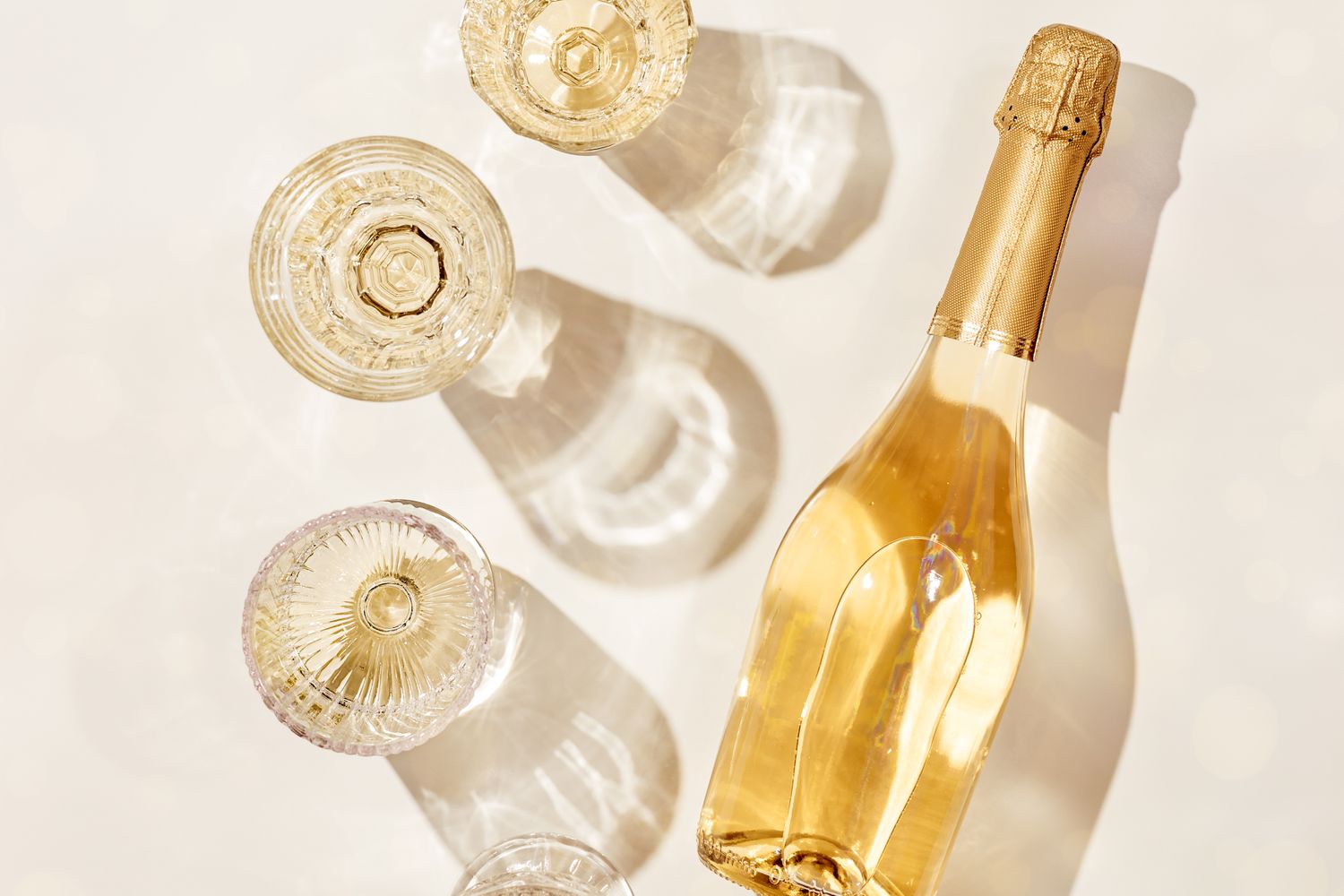 A bottle of champagne and several empty glasses arranged on a surface