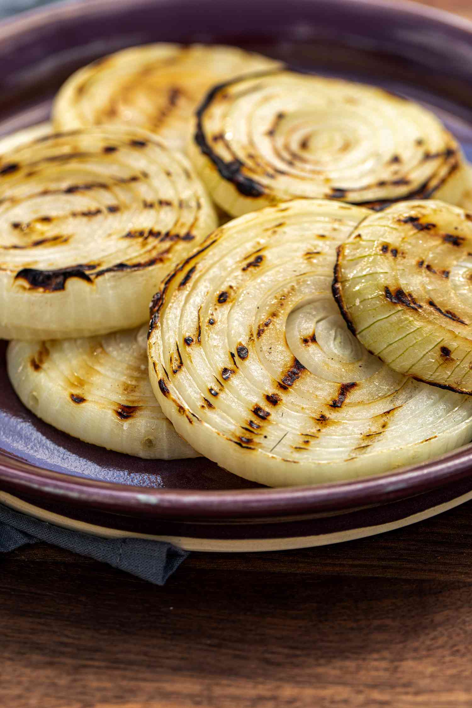 The best ever grilled onions piled on a purple rimmed platter.