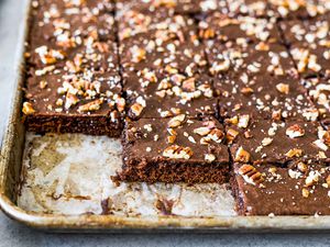 Texas chocolate sheet cake in a pan with a few pieces missing.
