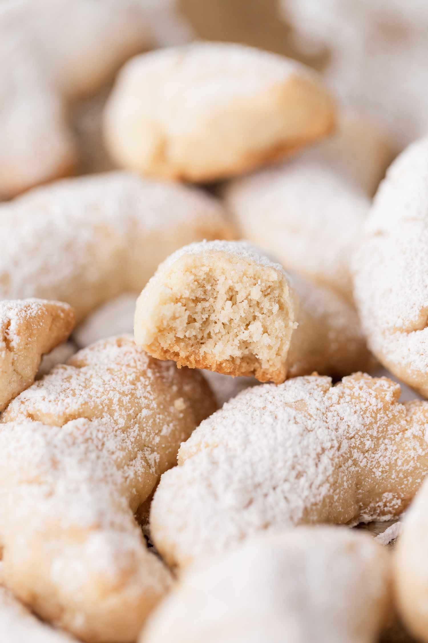 Side view of a close up of almond crescent cookies.