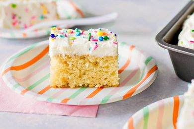 slice of vanilla cake on a paper plate a table with more slices on other paper plates 
